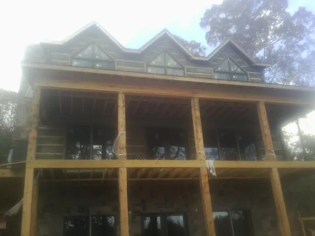 Dormers and porch framing on a large log home under construction — Roof Coating work by our crew in Wellington